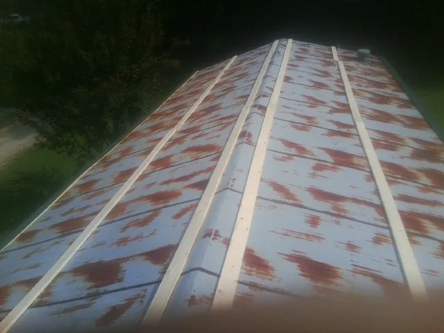 Rusted metal roof panels with new wood purlins before replacement in Chauncey