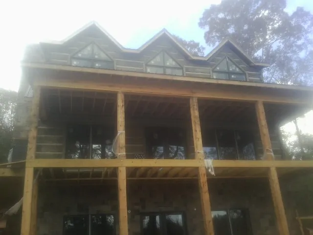 Dormers and porch framing on a large log home under construction — Roof Coating work by our crew in Chauncey