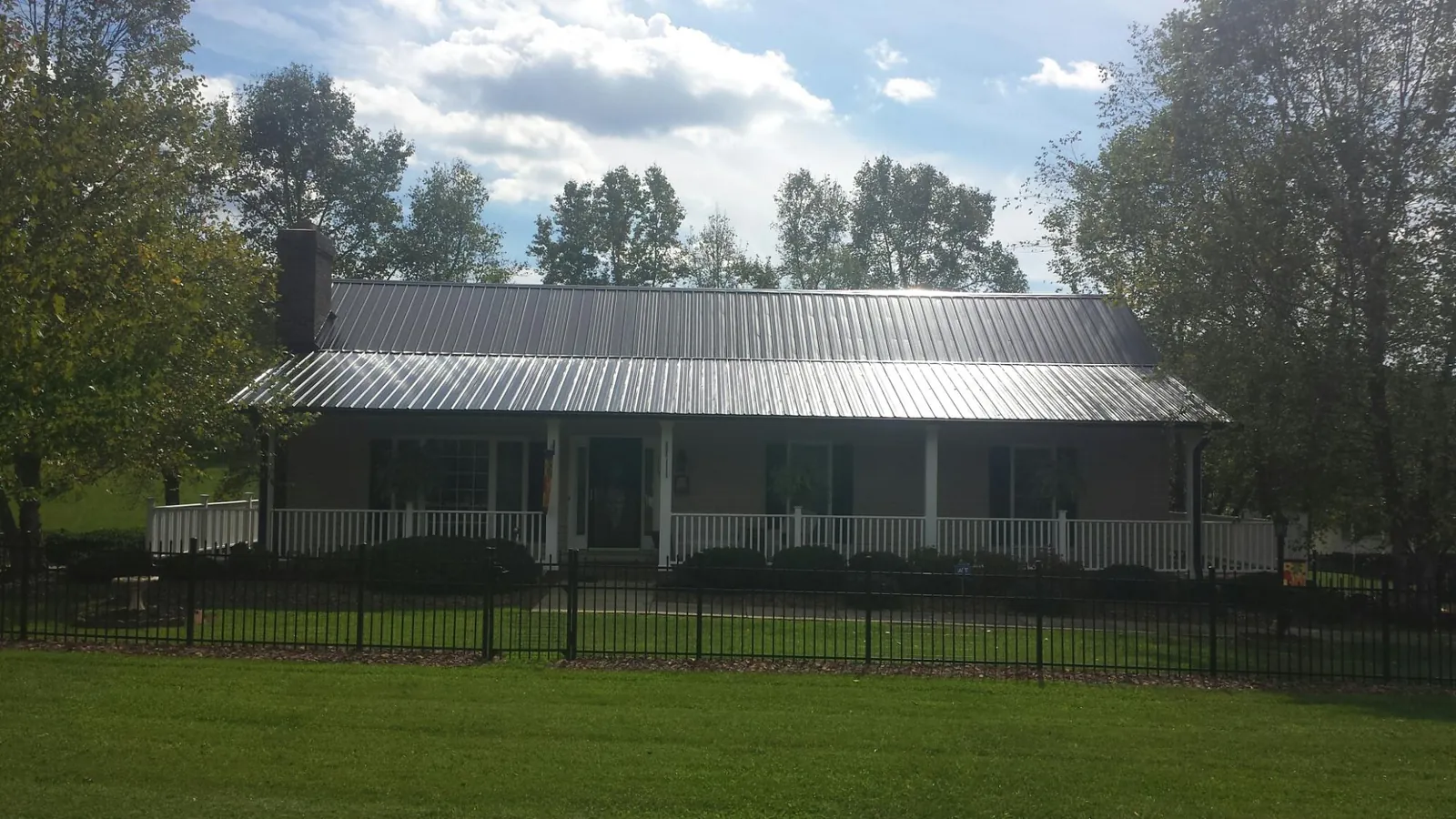 Gray metal roof on a brick ranch with a full width front porch — Gutter Guard Installation work by our crew in Chauncey