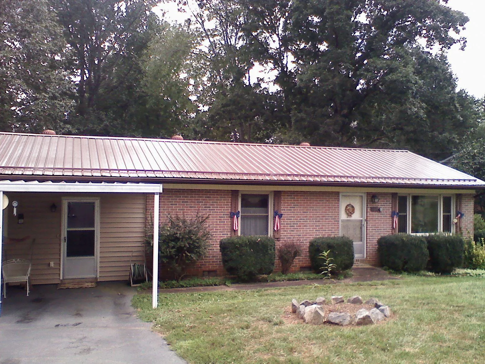 Bronze metal roof and carport on a brick ranch home — Roof Repair work by our crew in Chauncey