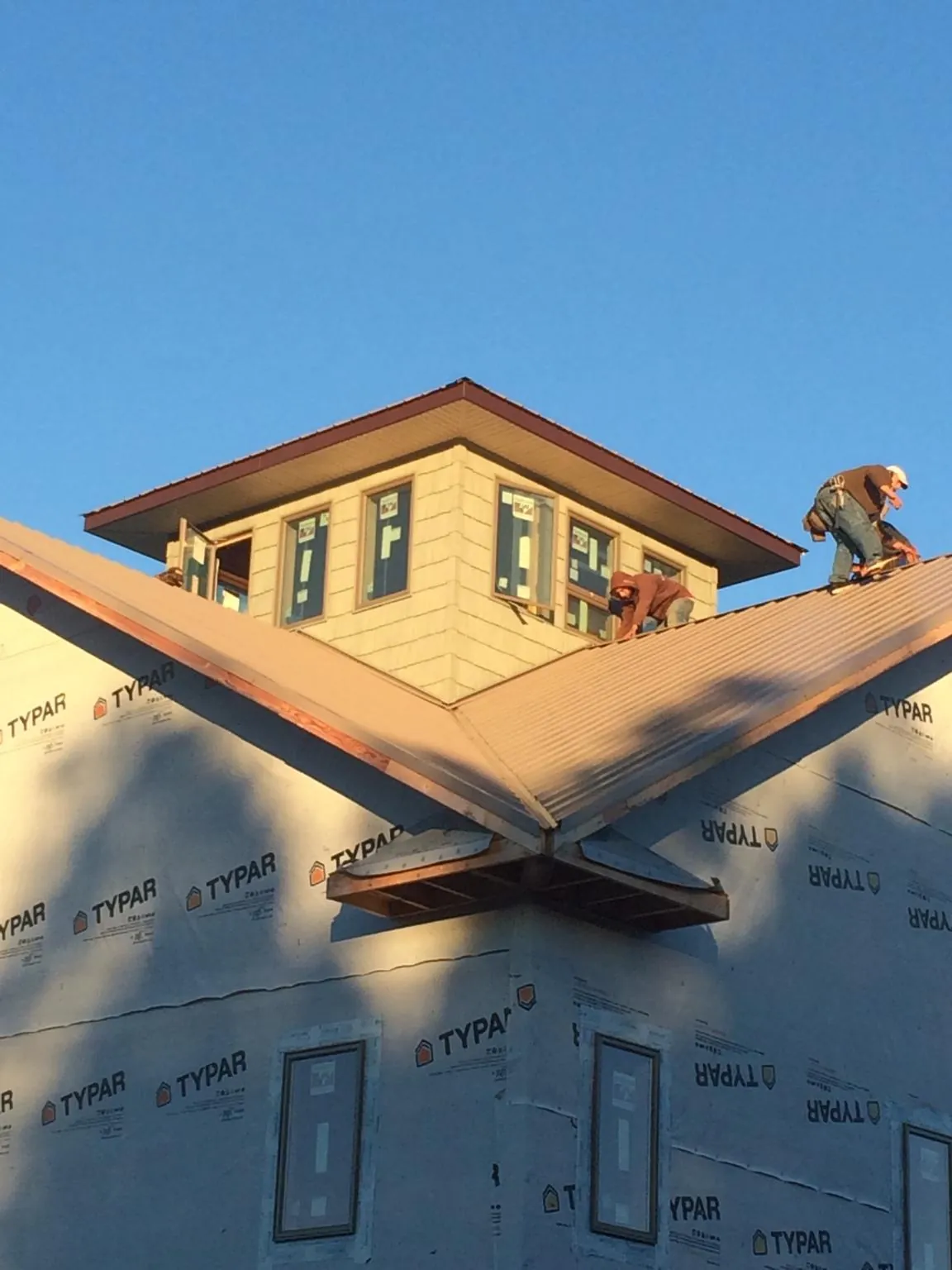 Roofers working around a rooftop cupola on a new metal roof at sunset — Roof Waterproofing in Chauncey by Roofing Brothers
